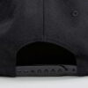 Structured canvas snapback cap. Flat brim, visible stitching detail. Adjustable back closure. Modern streetwear style. - View