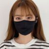 Close-up of a breathable three-layer face mask, charcoal gray color, showcasing fine stitching, adjustable ear loops, and a s