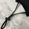 Close-up of a breathable three-layer face mask, charcoal gray color, showcasing fine stitching, adjustable ear loops, and a s