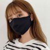 Close-up of a breathable three-layer face mask, charcoal gray color, showcasing fine stitching, adjustable ear loops, and a s
