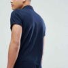 Close-up of embroidered polo shirt, fine pique knit texture. Royal blue fabric, crisp white logo stitching. Professional staf