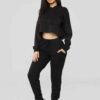 Women's black cropped tracksuit. Sleek, form-fitting design. Ribbed texture on the crop top and high-waisted bottoms. Visible