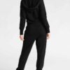 Women's lace-up tracksuit. Close-up shows soft, textured fabric. Dark grey with subtle stitch detailing. Sporty two-piece set