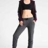 Women's lace-up tracksuit. Close-up shows soft, textured fabric. Dark grey with subtle stitch detailing. Sporty two-piece set