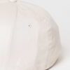 Close-up of a customizable twill cap. Visible stitching details, slightly distressed look, neutral tone. Garment is soft and