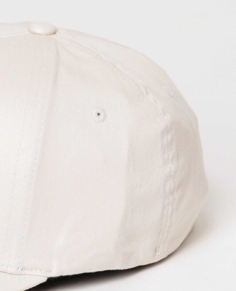 Close-up of a customizable twill cap. Visible stitching details, slightly distressed look, neutral tone. Garment is soft and